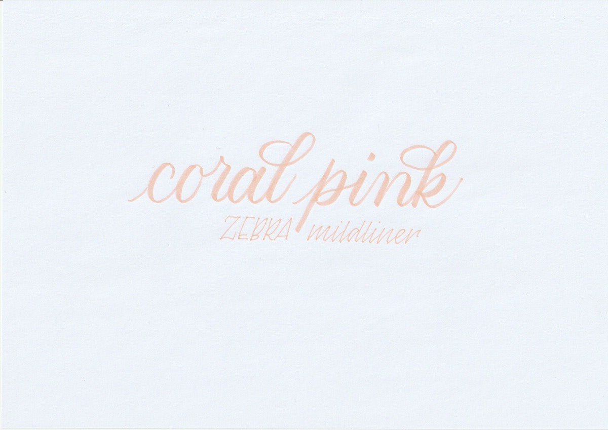 Handskriven text med orden "coral pink" och "ZEBRA mildliner" i korallrosa färg, skriven med Zebra Mildliner Brush Pen i färgen Coral Pink.