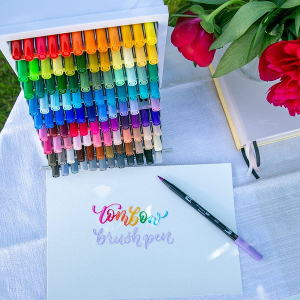 Display med samtliga pennor ABT Dual Brush pen. Framför ligger en av pennorna som skrivit på papper. - Tidformera